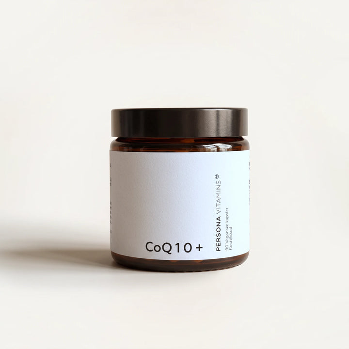Amber glass jar with a black lid and a CoQ10+ label on a cream background, straight-on view