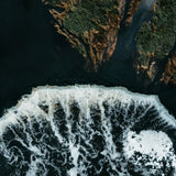 Aerial view of white waves breaking on dark water beside green islands, photo by Kristaps Ungurs