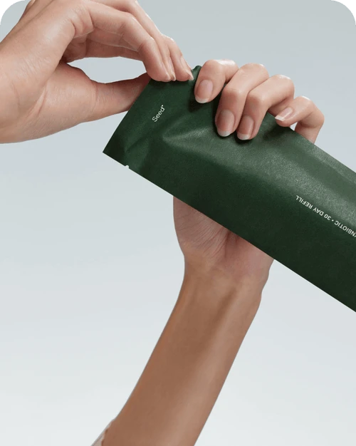 Hands opening a dark green refill pouch